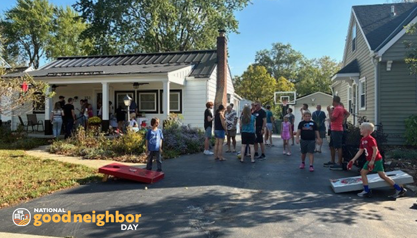 Group of neighbors gather in a front yard to play games and talk.